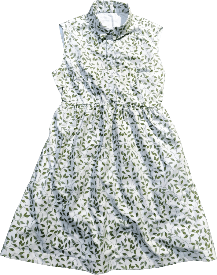 A photo of a sleeveless shirt dress made out of white fabric with green leaves on it.